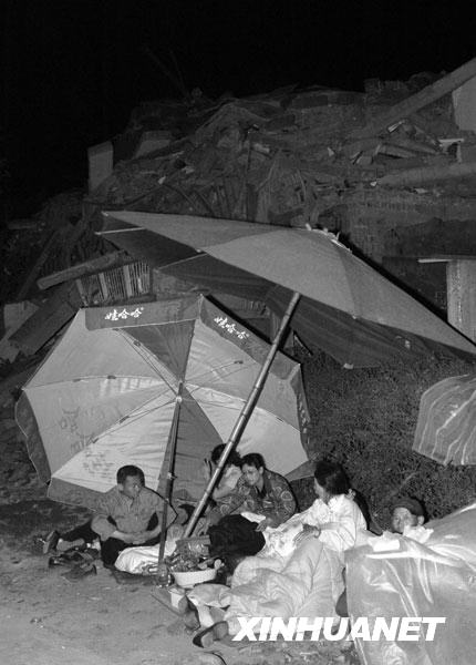 2008年5月13日凌晨，绵竹市汉旺镇的一些居民露宿在垮塌的建筑前。