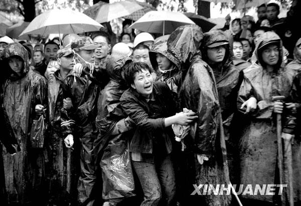2008年5月13日，一名等待孩子消息的家长看到一名遇难学生的遗体被抬出后，奋力向前冲去。当天，救援人员继续在四川都江堰市聚源镇聚源中学冒雨进行救援工作。