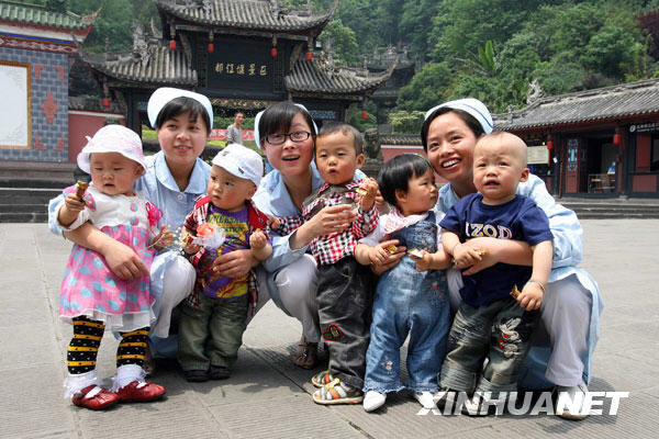 5月11日，三名护士王丽（左二）、罗云莉（左四）和张兰（右二）在曾经护理过“地震宝宝”的广场上与5名婴儿合影。