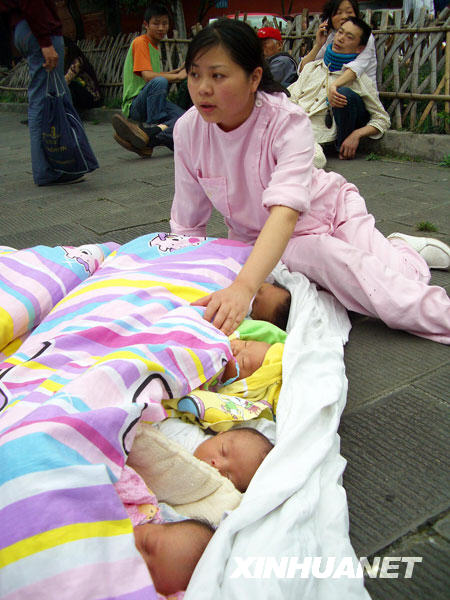 这是2008年5月12日拍摄的都江堰市人民医院护士罗云莉正在照看从医院大楼里转移出的婴儿的资料照片。