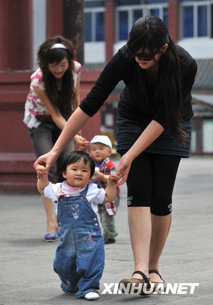 5月11日，已经满岁的“地震宝宝”们在妈妈的搀扶下走路。