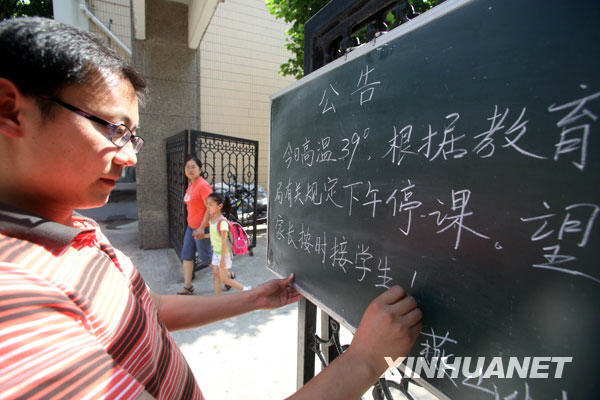 6月24日，一名郑州市民在街头用报纸遮挡烈日。