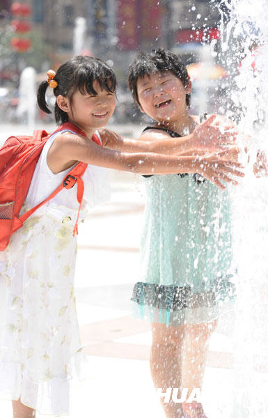 6月24日，孩子们在郑州市二七广场的喷泉旁消暑。
